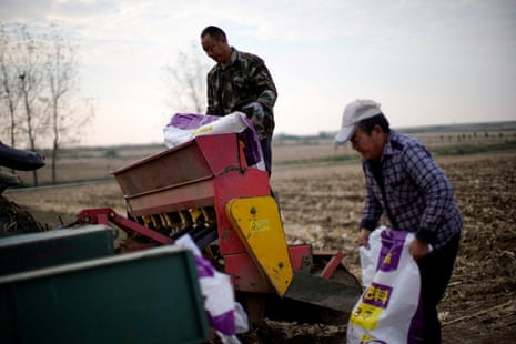 Farmers load sacks of fertiliser into a seeder on a wheat field in Nanyang, Henan province, China, 2021.