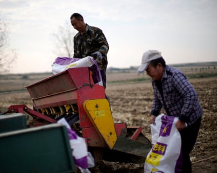 Farmers load sacks of fertiliser into a seeder on a wheat field in Nanyang, Henan province, China