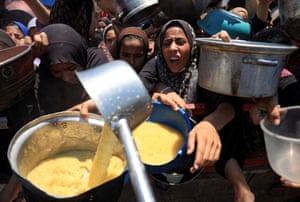 One woman is served amongst flocks of people holding out bowls, desperate to get food