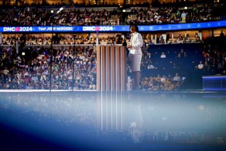 A woman stands at a lectern in front of a large audience.