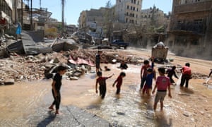 Children play with water from a burst waterpipe at a site hit yesterday by an airstrike in Aleppo’s rebel-controlled al-Mashad neighbourhood