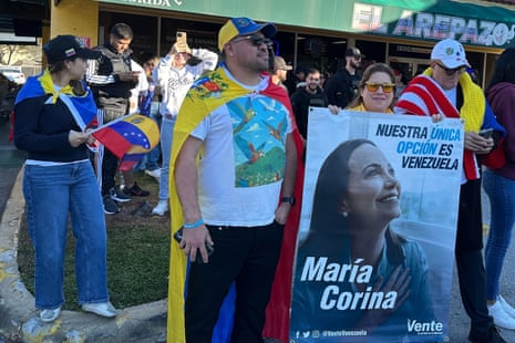 From left, Venezuelans David Nuñez, Lisbeth Garcia, Victor Gimenez gather outside El Arepazo restaurant with a banner of opposition leader and Nobel peace prize winner Maíia Corina Machado amid celebrations following news of Venezuelan president Nicolás Maduro’s capture, earlier today in Doral, Florida.