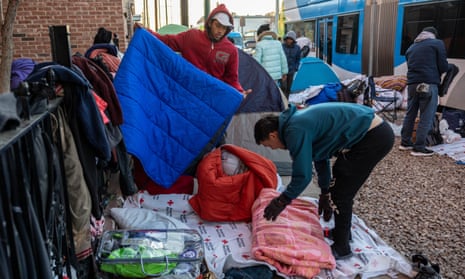 Immigrants pack up blankets after sleeping outside a migrant shelter in January 2023 in El Paso, Texas.