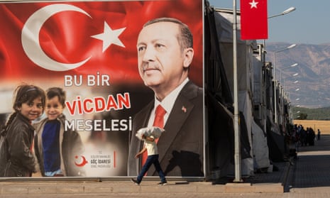 A Syrian refugee walks past a poster of President Recep Tayyip Erdoğan that reads: ‘It’s a matter of conscience’