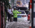 Officials direct traffic on a flooded road in China