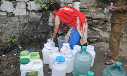 An Indian woman fills buckets in Shimla