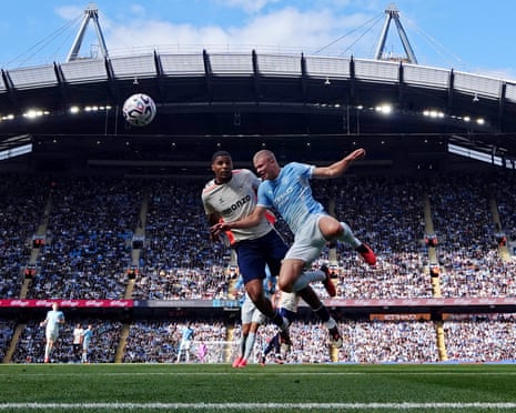 Erling Haaland and a Coventry City defender jump for a header in a packed stadium