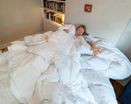 Reviewer Jane Hoskyn lies on a double bed covered in duvets that she is reviewing.