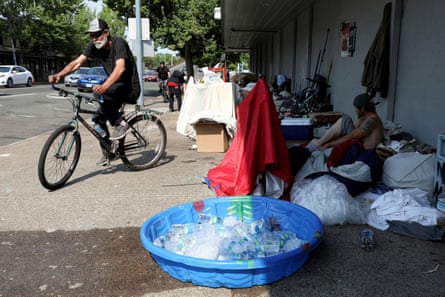 George Ivanoff, 56, rides his bike away from his camp on Thursday in downtown Salem, Oregon, where a small pool holds ice and bottles of water.