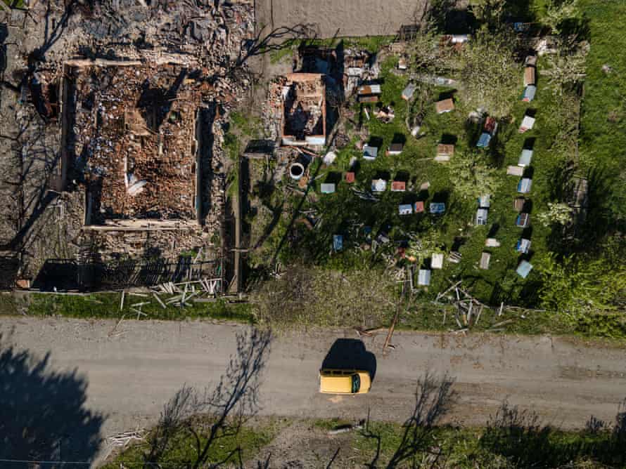 A car drives by destroyed houses in Sloboda-Kukharivska, Ukraine.