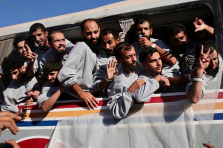 A large number of the Palestinian prisoners hang out of the windows of a bus