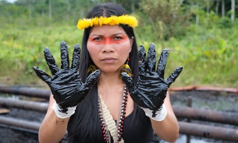 Waorani activist Nemonte Nenquimo holds up her gloved hands covered in oil