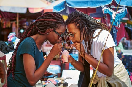 Keshia Sakarah shares a snow cone with a friend in Georgetown, Guyana.