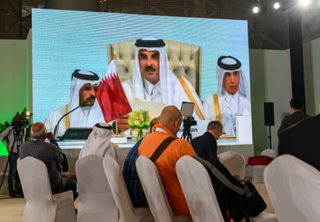 Journalists watch a speech by Qatar’s Emir Sheikh Tamim bin Hamad Al-Thani on a screen at the media centre during the opening of the emergency summit in Doha.