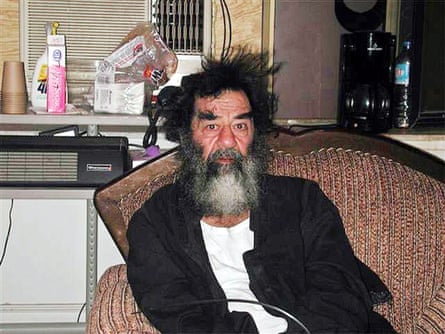 Saddam Hussein sits on a couch shortly after his capture by US forces in a farm house outside Tikrit, Iraq, 14 December 2003.