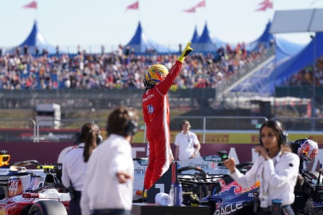 Lewis Hamilton stands connected his car pinch his correct limb raised
