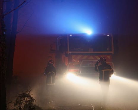 Firefighters’ silhouettes are seen through thick smoke as a wildfire rages through the Landes forest in Luglon, southwestern France.