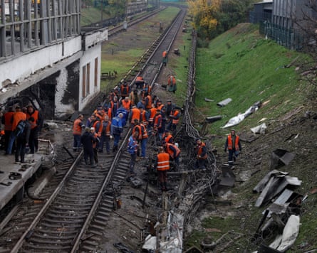 Workers mostly in hi-vis orange work on a damaged railway track
