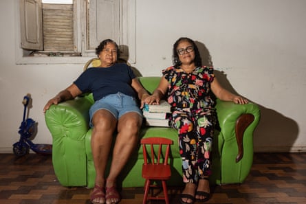 two women sit on a sofa with photo albums between them