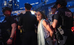 A dusk shot of four officers leading away a handcuffed woman