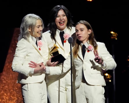 The musicians Phoebe Bridgers, Lucy Dacus and Julien Baker of Boygenius, wearing white suits, accepting an award at the Grammys