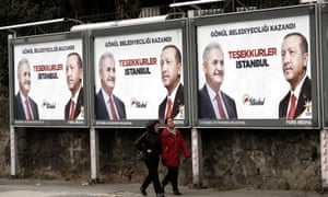 People walk past AKP billboards with pictures of Erdoĝan and mayoral candidate Binali Yıldırım in Istanbul.