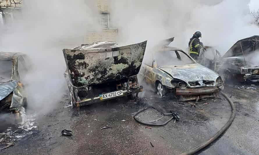 A firefighter tries to put out the fire of burning vehicles after shelling at a residential area in Kharkiv.