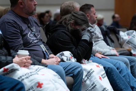person puts head in hands while sitting next to other people