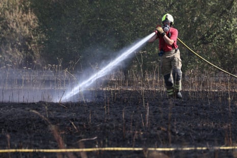 A firefighter works to contain a grass fire which started at Lake Farm Country Park in Hayes on 8 August.