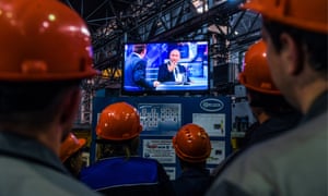 Workers watch a live broadcast of the question and answer session