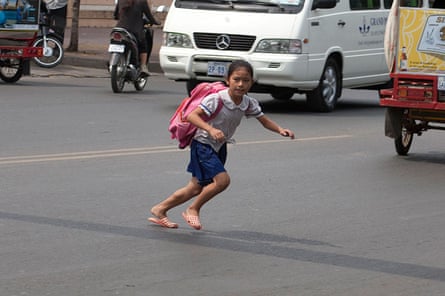A young girl crosses a busy road in Cambodia