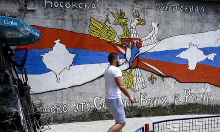 A Kosovo Serb man walks next to graffiti showing the map of Kosovo in a Serbian flag on a street in the majority ethnic-Serb northern part of the city of Mitrovica.