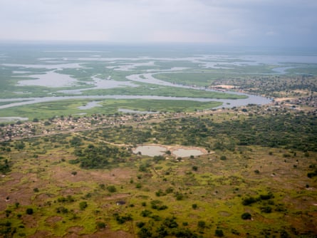 An aerial view of a town in a green landscape with lots of bodies of water, including a river