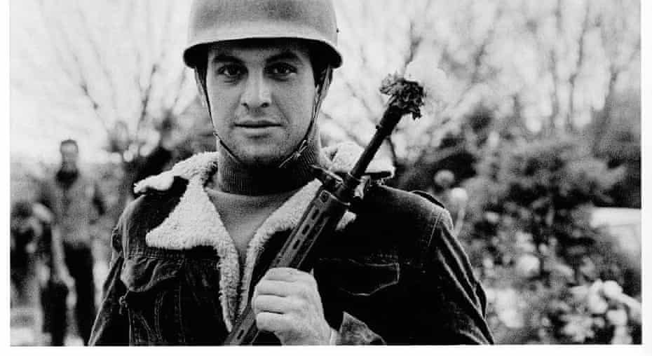 An Iranian revolutionary with a flower in his rifle.