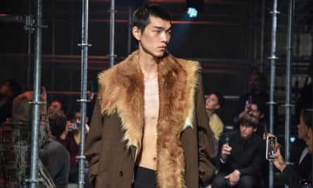 A bare-chested model wearing a jacket with faux-fur detailing