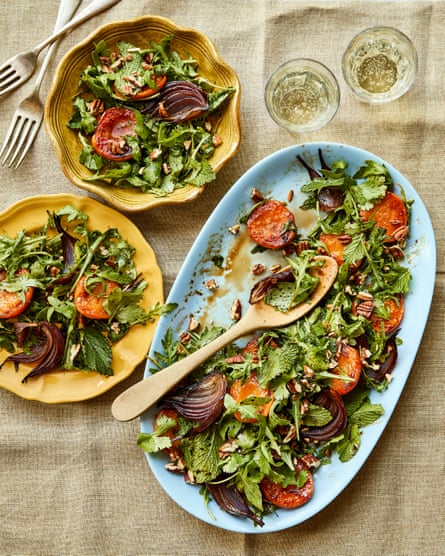 Two yellow plates of served salad, with drinks and cutlery on the side