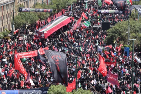 Aerial view of street filled with people waving flags and holding signs.