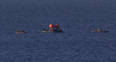 Kurtarma ekipleri, Artemis II mürettebat üyelerini şişme ön güverteden Pasifik Okyanusu'ndaki USS John P Murtha gemisine transfer etmeye hazırlanıyor.