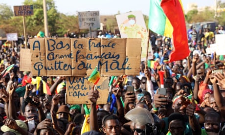 A person holds a sign that reads 'Down with France, the French army' in a crowd of people