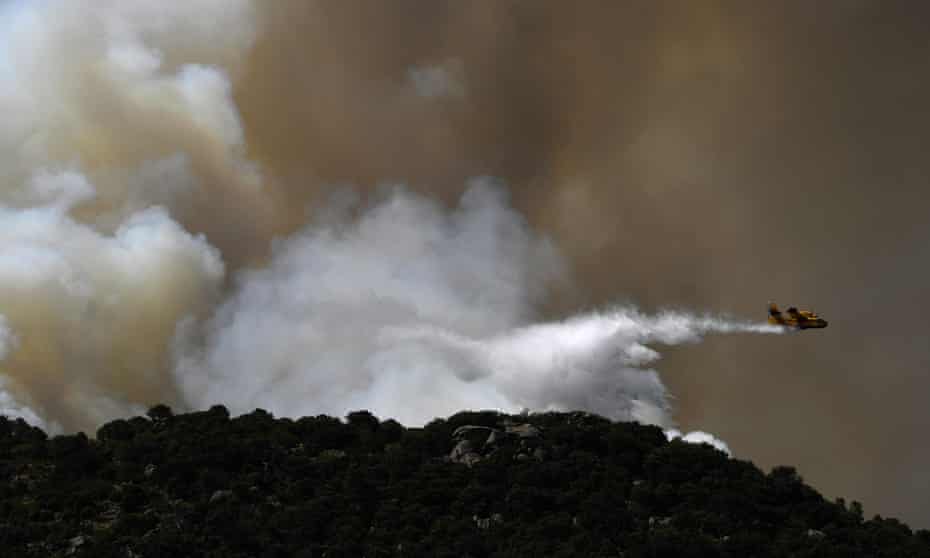 A plane drops water over a wildfire on the edge of Cenicientos, central Spain, in June.
