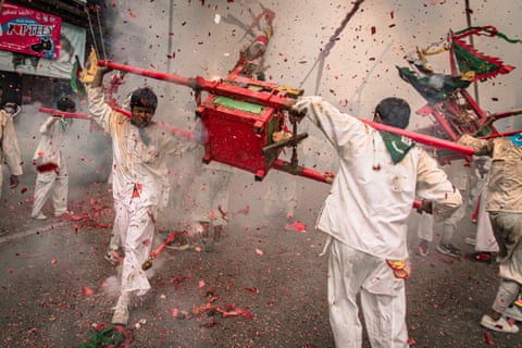 Devotees carry a red shrine on poles through smoke during Thailand's vegetarian festival
