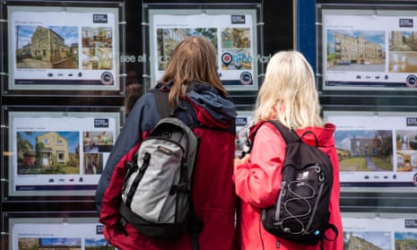 People look at properties in the window of an estate agent