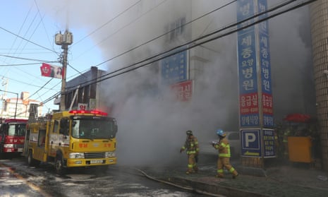 Firefighters try to put out a fire at a hospital building engulfed by heavy grey smoke in Miryang .