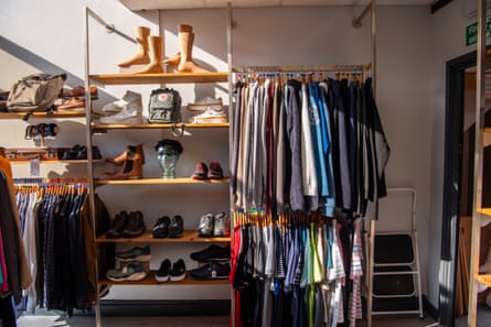 A rack of clothes, and a shelf unit stacked with shoes and model wooden feet