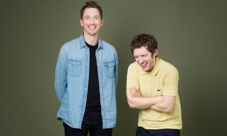 John Robins, standing, wearing a blue denim shirt and Elis James, standing next to him and bent over laughing, in a yellow polo shirt