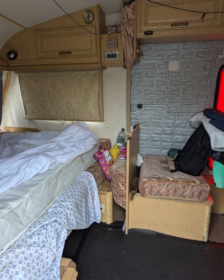 A shabby-looking interior of a caravan with a bed in