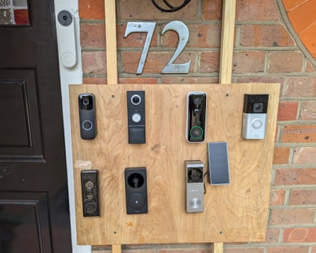 A plank of wood with 8 video doorbells attached to it