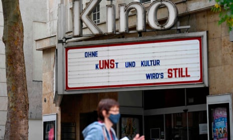 A woman passes by a closed cinema with a board displaying ‘Without art and culture it’s getting quiet’ in Stuttgart, Germany.