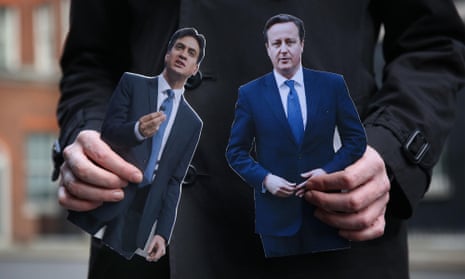 LONDON, ENGLAND - MARCH 18: A TV reporter holds cut out photographs of Prime Minister David Cameron and opposition Labour Party Leader Ed Miliband ahead of today’s budget in Downing Street on March 18, 2015 in London, England. The Chancellor is presenting his 5th Budget to Members of Parliament today, the last before the General Election on May 7, 2015. (Photo by Peter Macdiarmid/Getty Images)