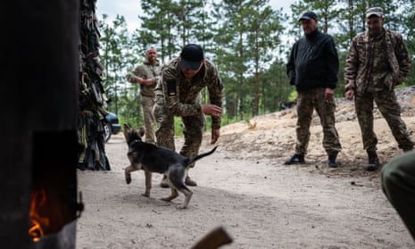 Servicemen of the Territorial defence play with a puppy in the forest near the Belarusian border, Ukraine.